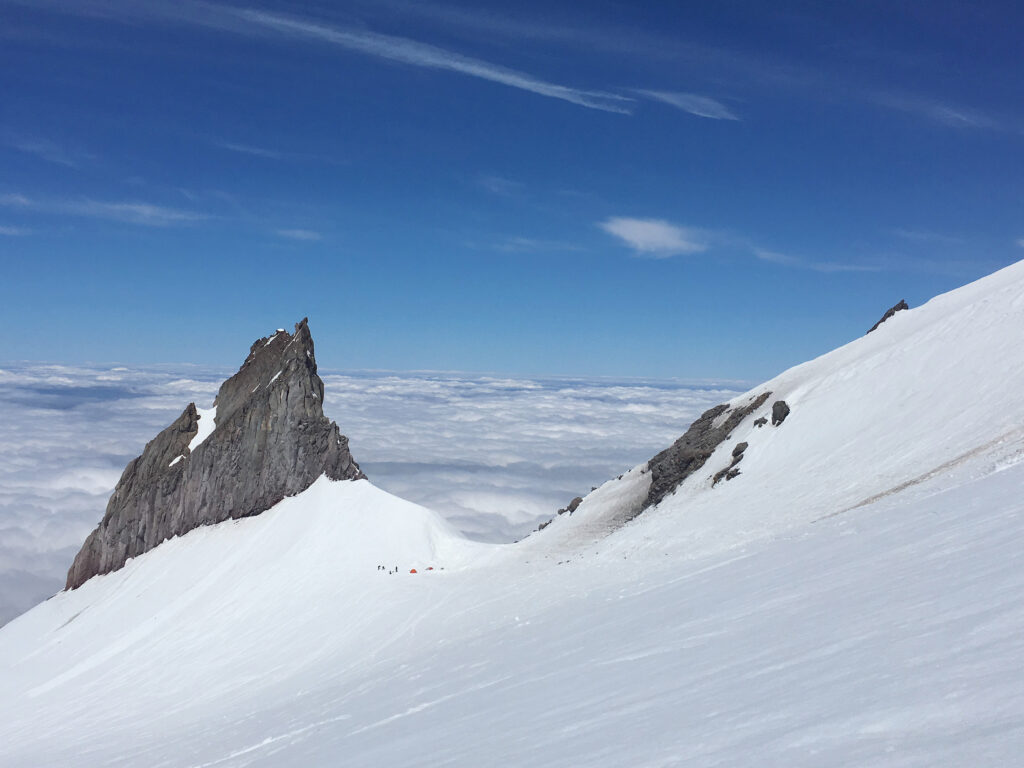 Illumination Rock with tents below it in the saddle