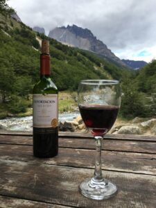 Bottle and glass of wine overlooking a creek and mountains