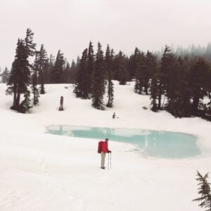 My partner hiking next to an icy lake in the snow
