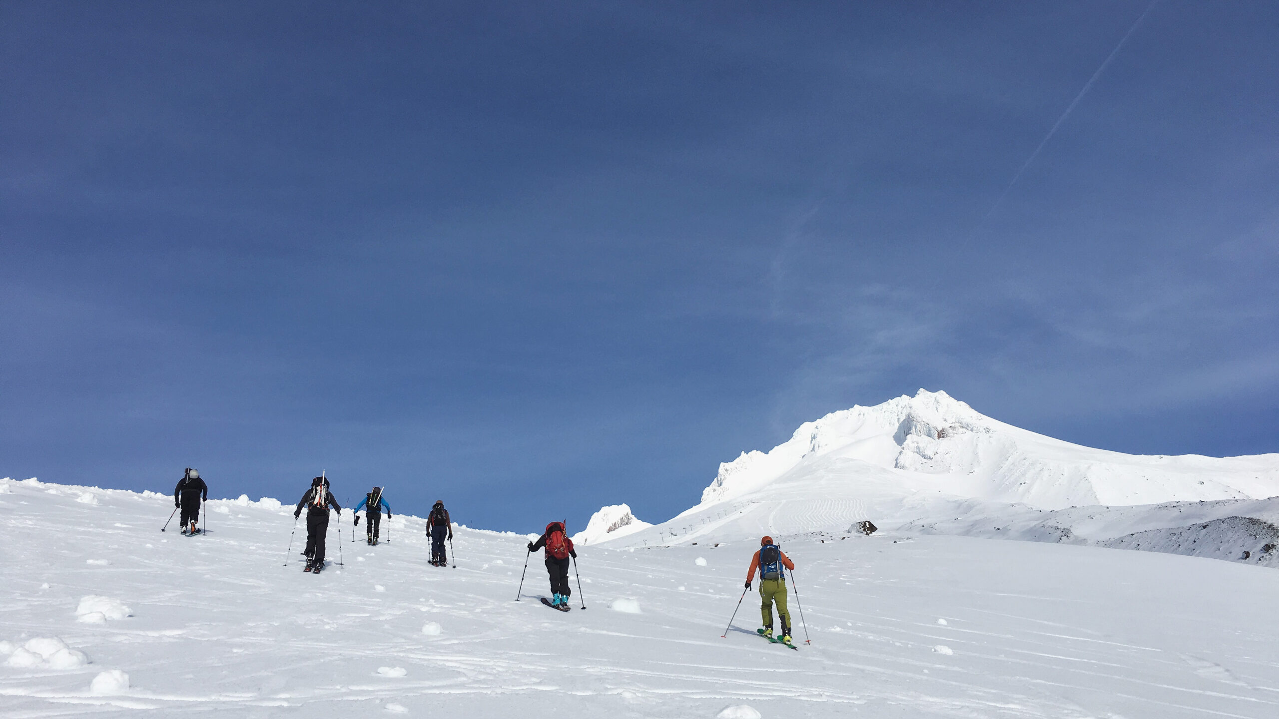 Group of skiers skinning up Mt. Hood, well spaced out from each other