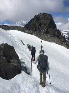Crossing a snow field towards the rocky summit block
